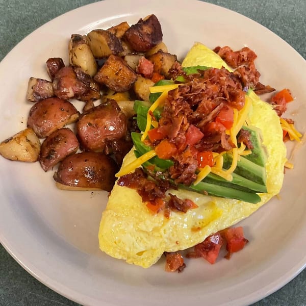 A Shakers American Café omelet with avocado, bacon, cheese, and tomatoes, served with roasted potatoes.