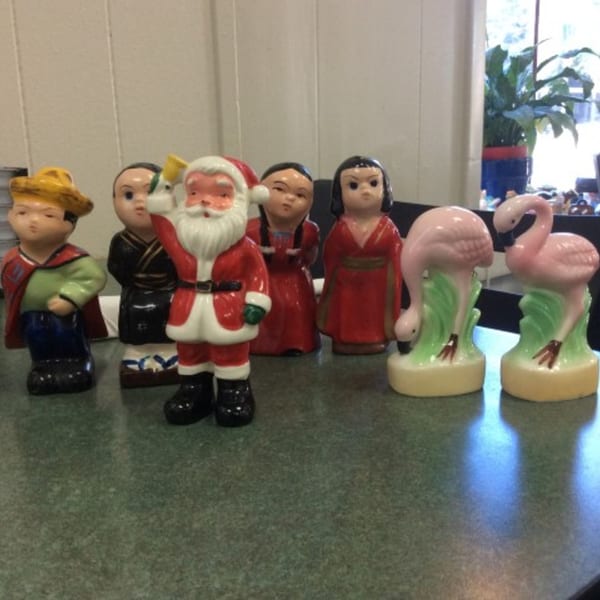 A collection of diverse figurines, including Santa Claus and two pink flamingos, on a green table.