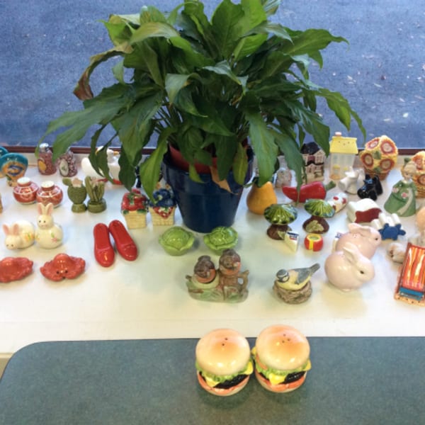 A collection of whimsical salt and pepper shakers, including burgers, rabbits, and shoes, displayed at Shakers American Café.